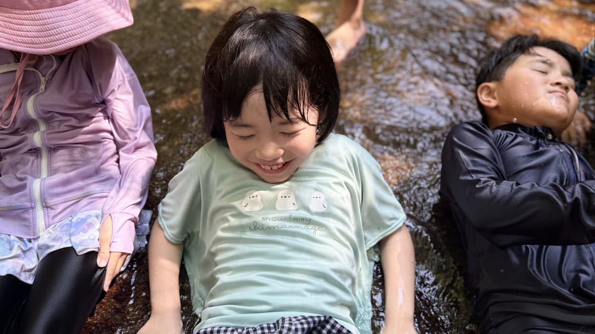 柏原公園の川で気持ちよさそうに水に触れる小学生