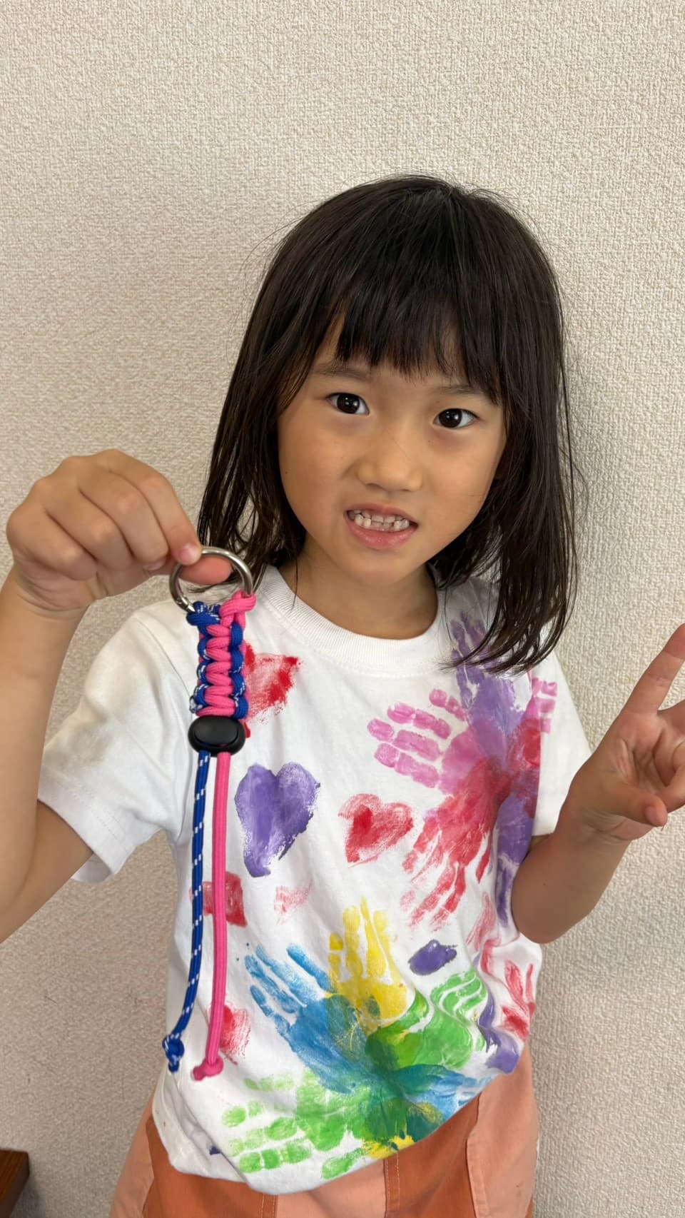 完成したパラコードのマルチホルダーを見せる小学生