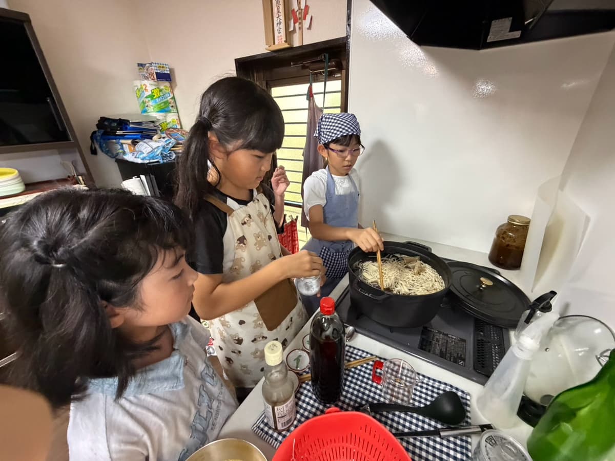 給食づくりで鍋を混ぜる小学生たち