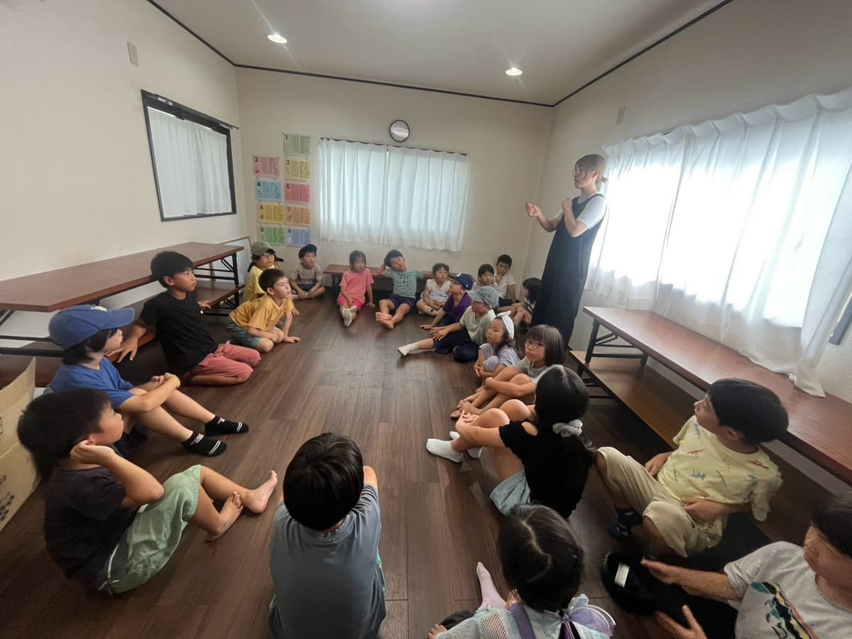 まどいタイムで輪になって話を聞く小学生たち