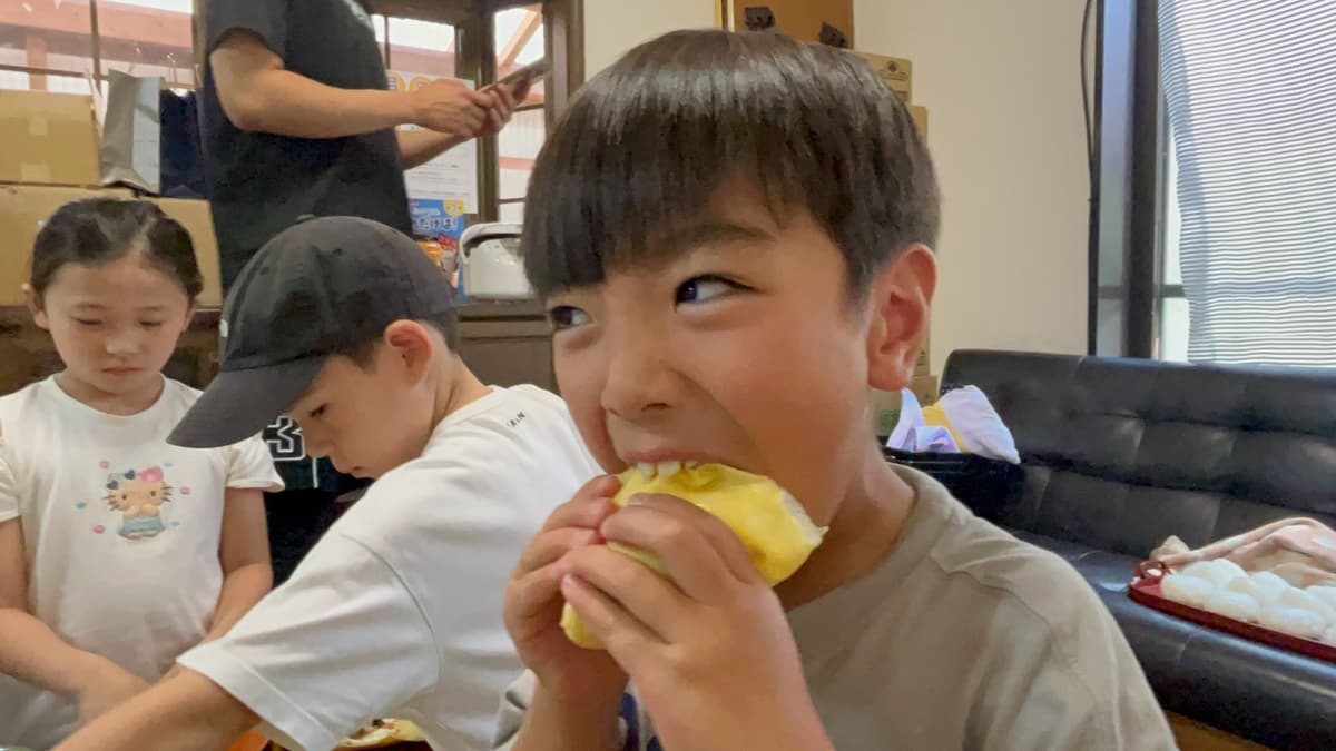 出来上がった餃子を頬張る小学生