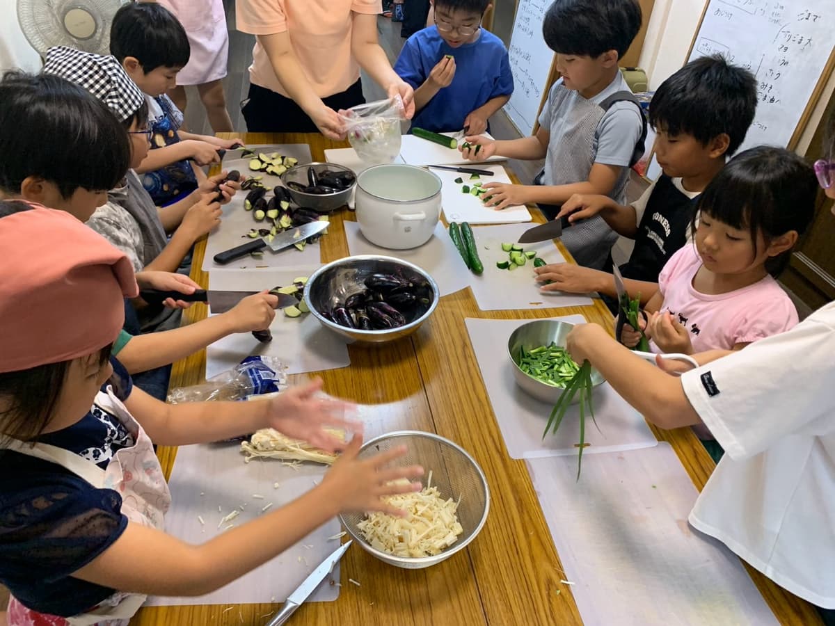 野菜を切って給食づくりをするまどいっ子たち