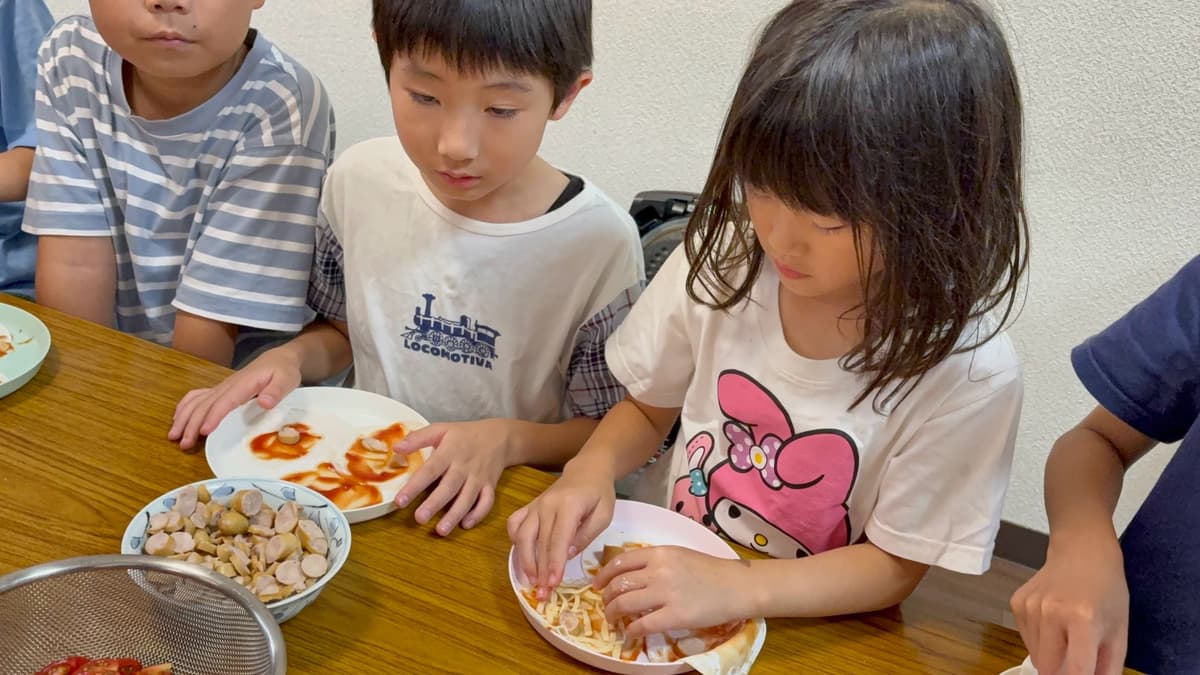 餃子の皮に具材をトッピングするまどいっ子たち