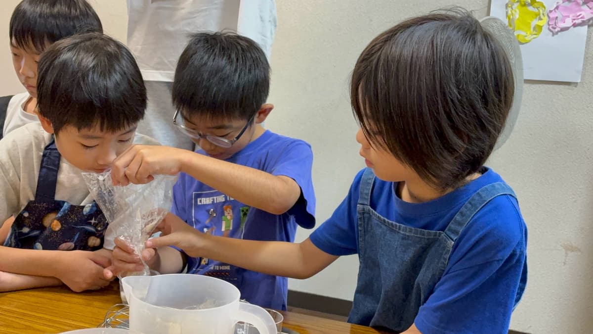 お菓子教室で協力してゼリー液を注ぐまどいっ子たち