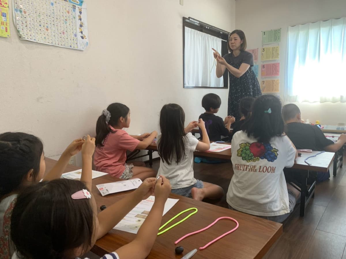 パラコード教室で講師の説明を聞く小学生たち