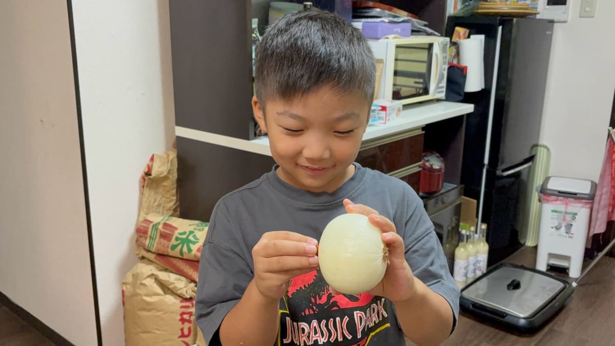 給食づくりで玉ねぎの皮をむく小学生