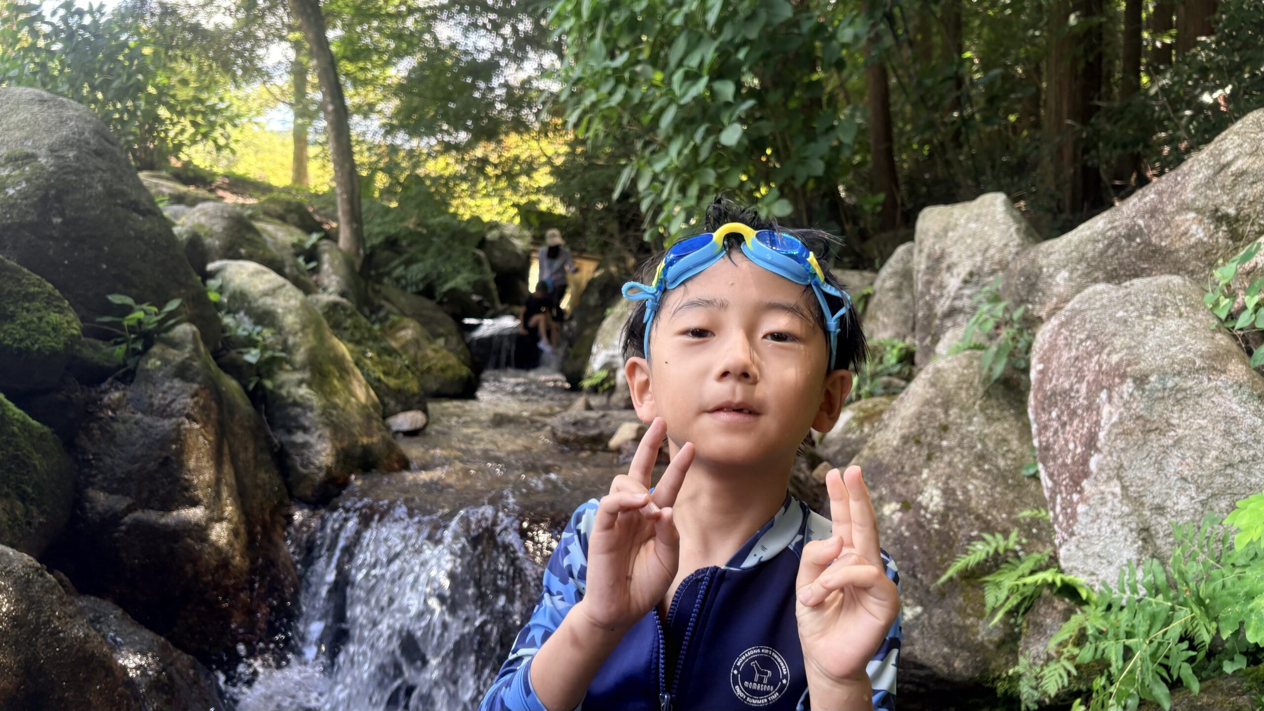 昭和の森の滝の前でピースサインをする小学生