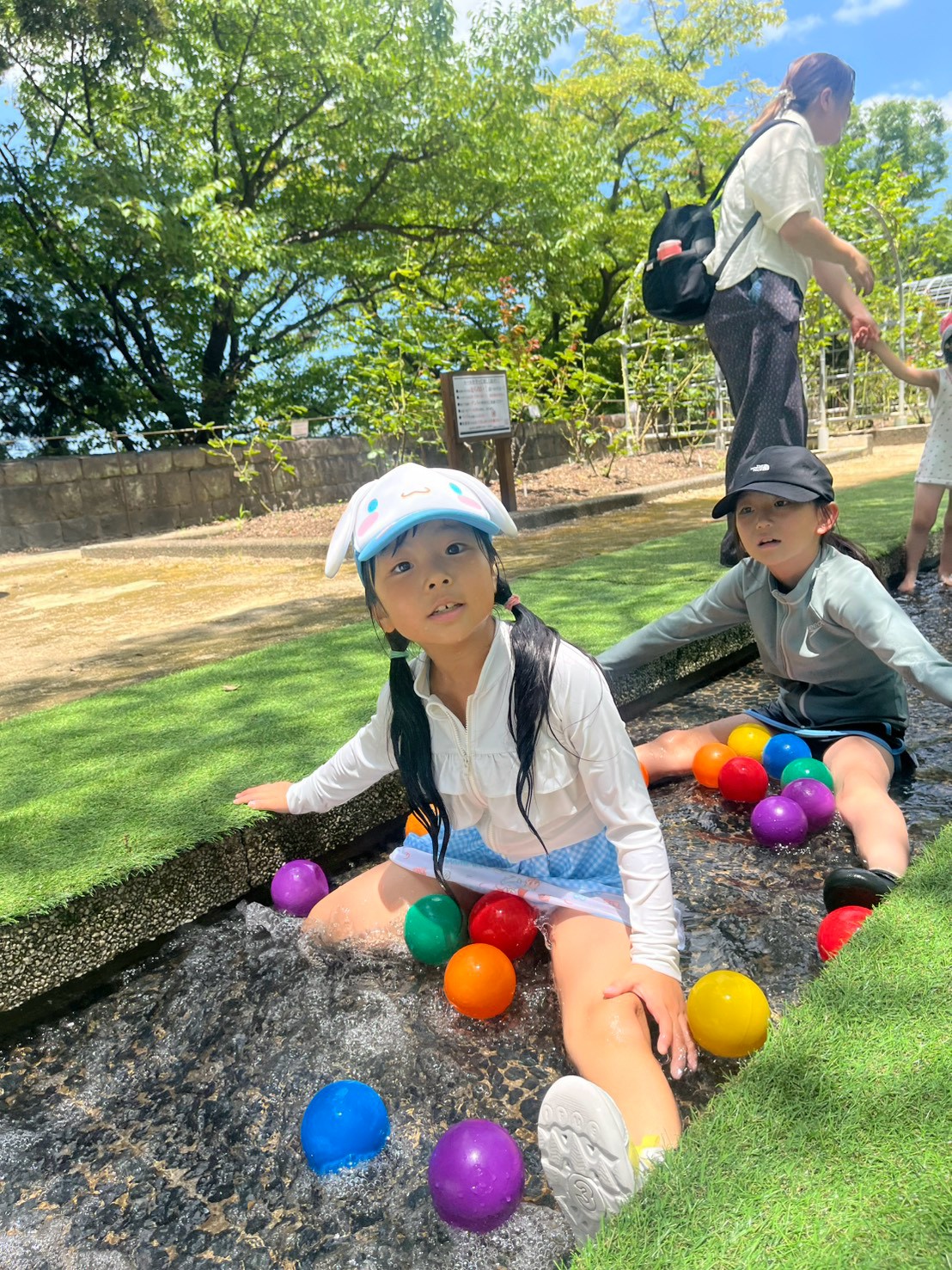 花畑園芸公園の水遊び場で水しぶきをあげて走る子ども