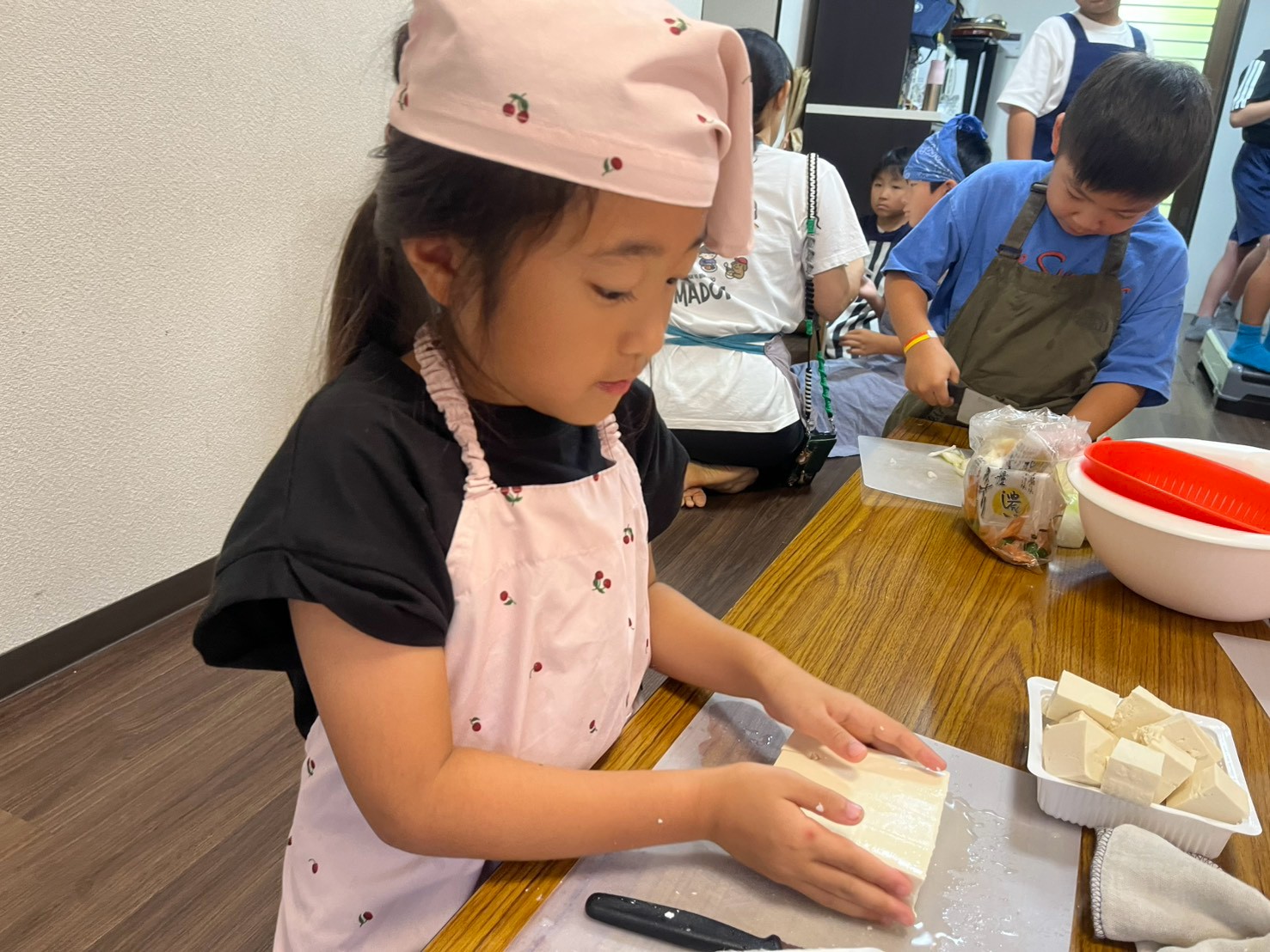 給食づくりで豆腐を切る小学生