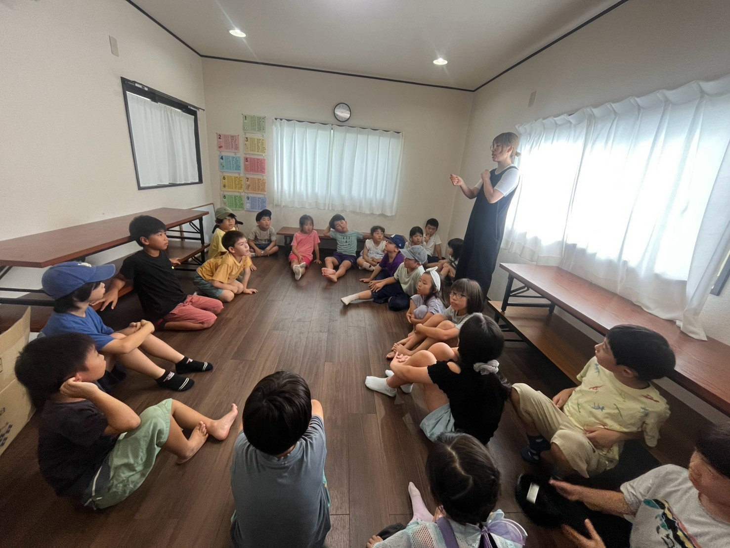 まどいタイムで輪になって話を聞く小学生たち