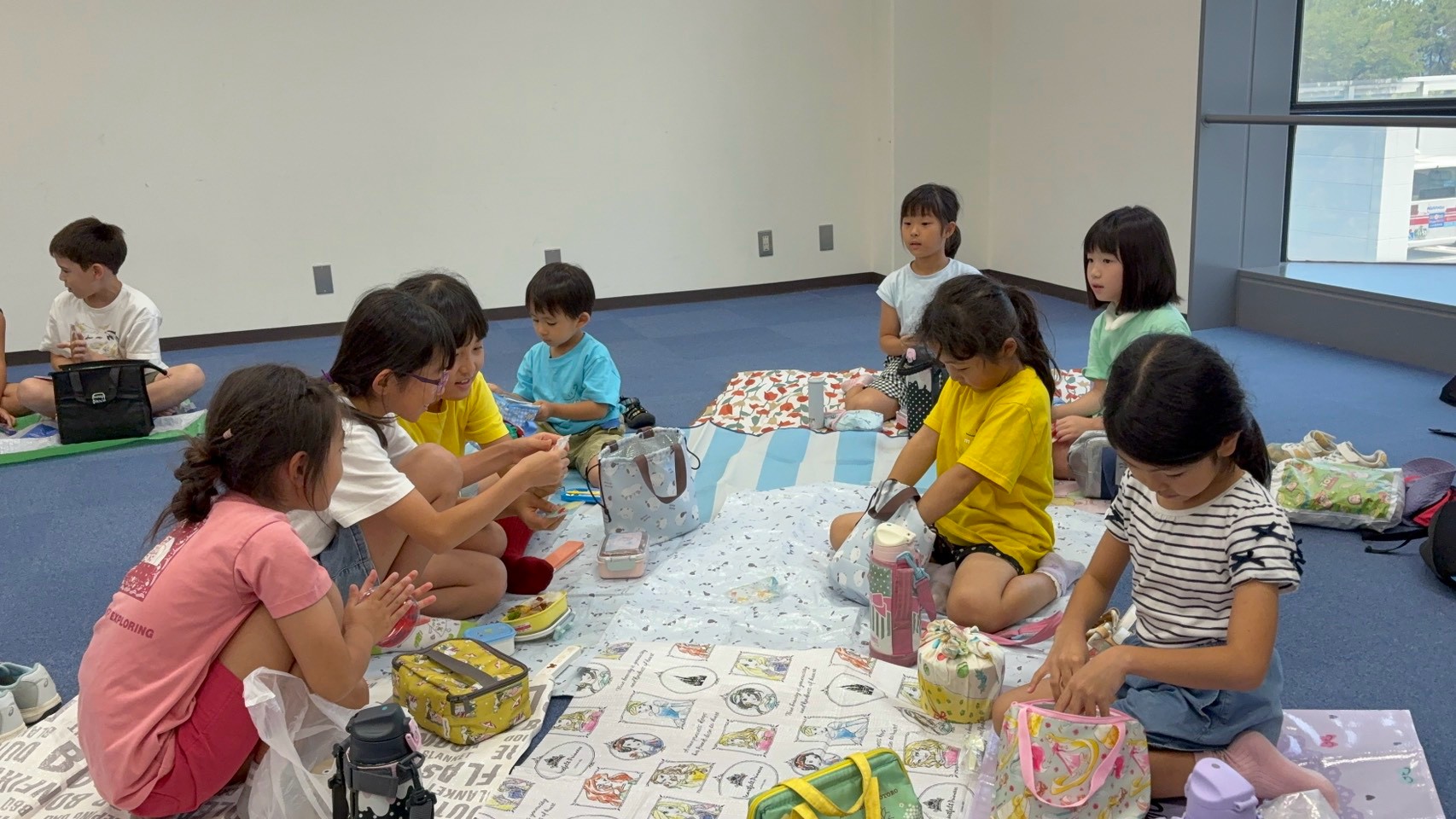 福岡タワーの館内でお弁当を食べる学童の子どもたち