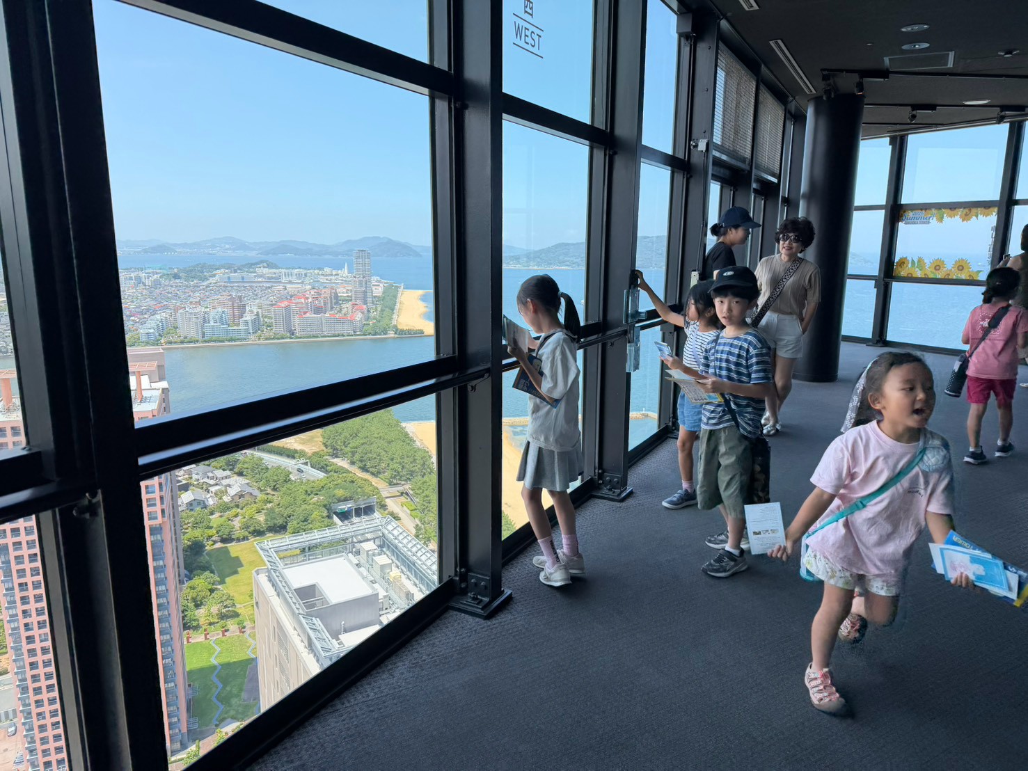 福岡タワー展望室から景色を眺めながらスタンプラリーを楽しむ子どもたち