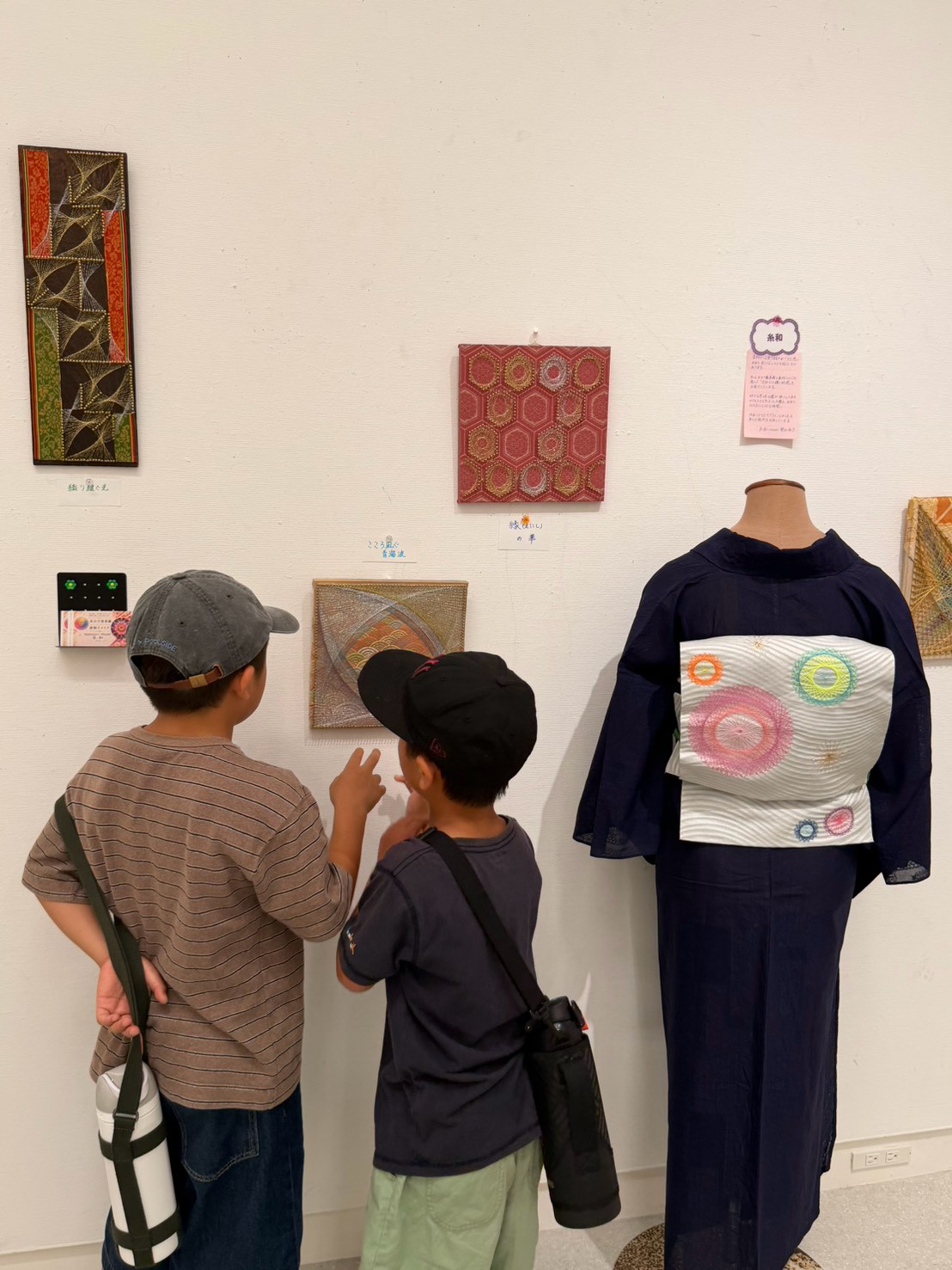 福岡市美術館で曼荼羅アートの展示を眺める小学生たち