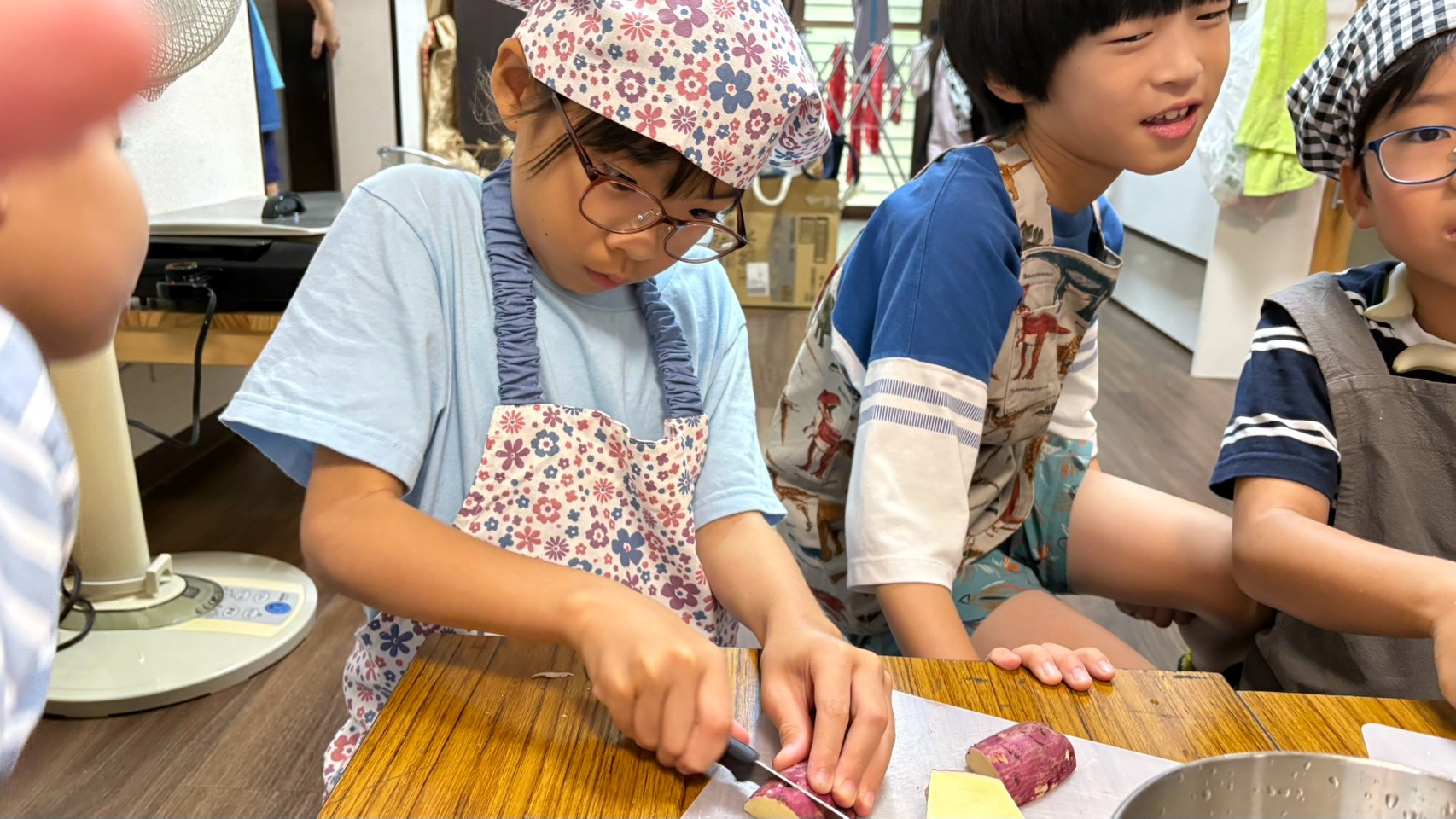 給食づくりでさつまいもを切る小学生