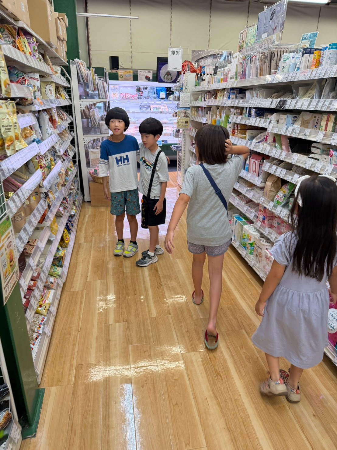 お店の売り場でお菓子を選ぶ小学生たち